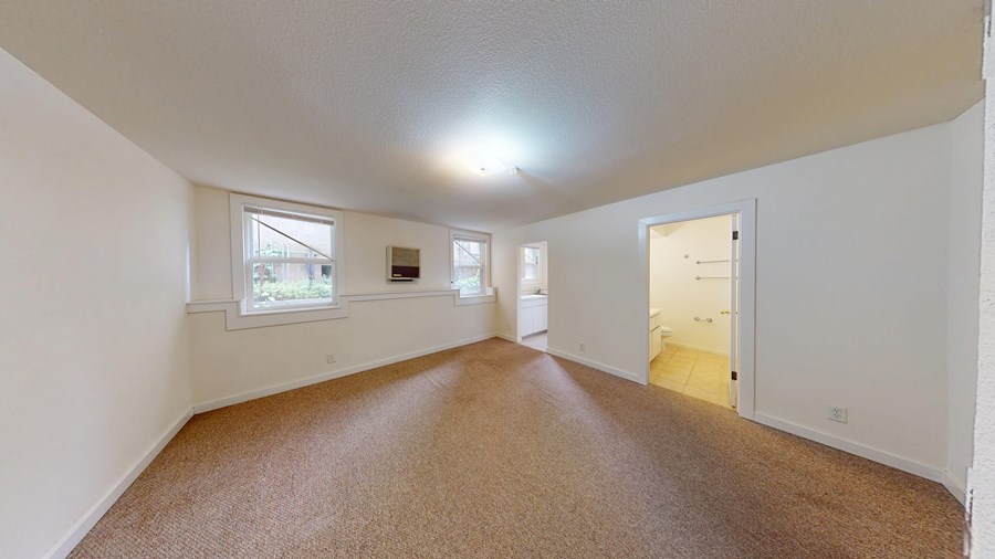 A room with white walls and brown carpet.
